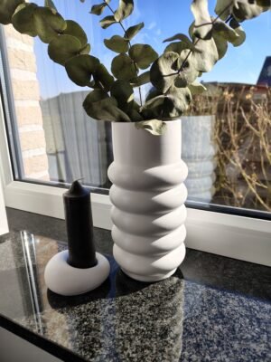 New Page Concrete candle holder with a dark candle next to a vase